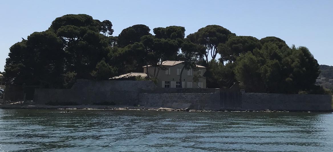 The estate seen from the lagoon, behind its stone wall and tall pines