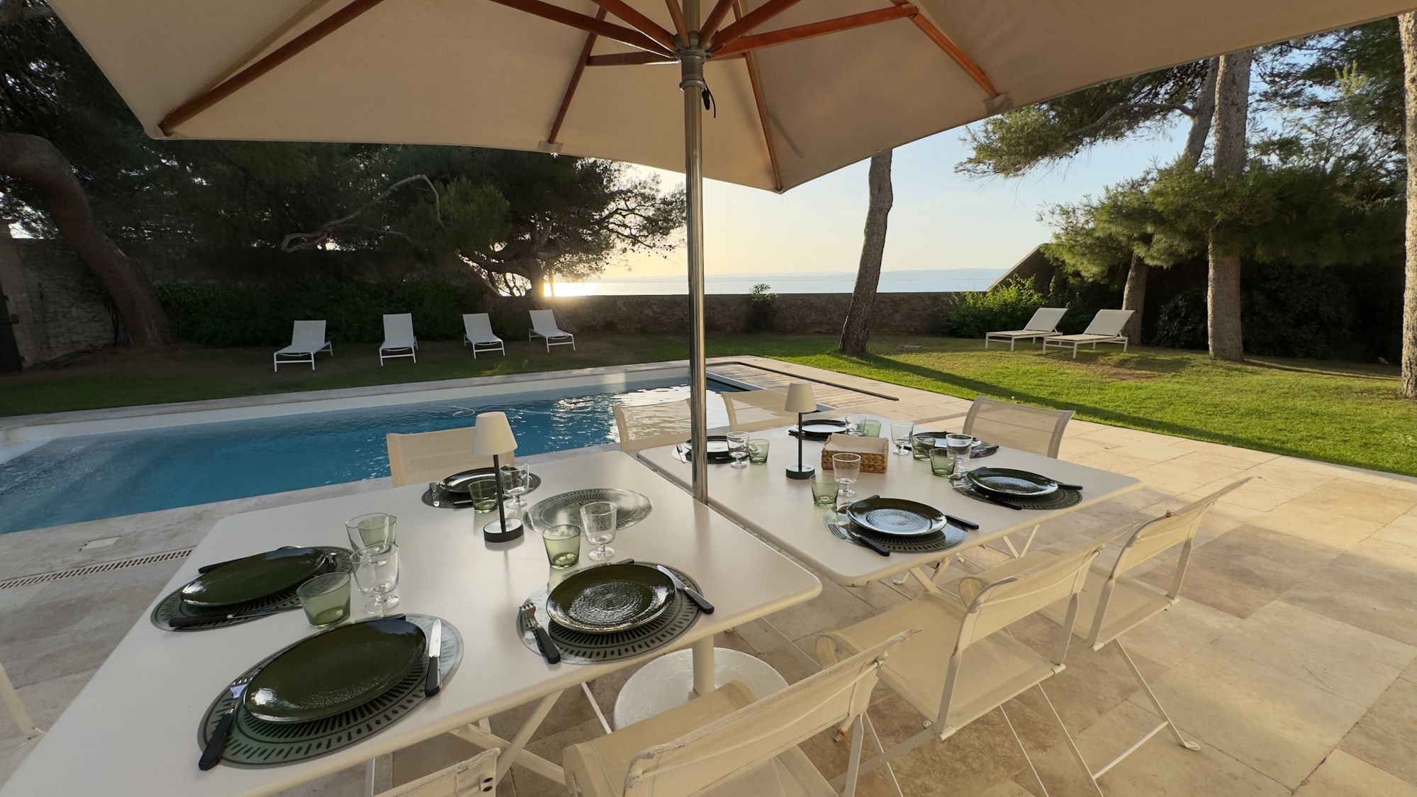 Table laid beside the pool, facing the lagoon at sunset