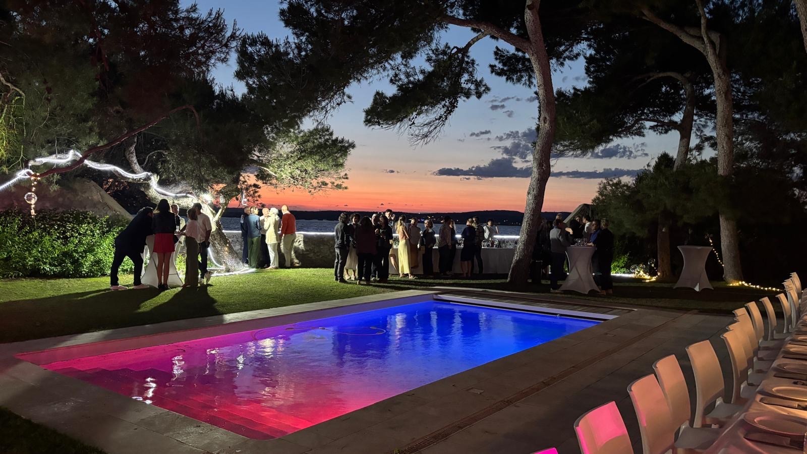 Company evening beside the lit pool, at sunset over the lagoon